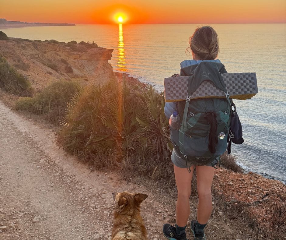 Hiker and small dog on the Fisherman's Trail at sunset, looking out over the Atlantic.
