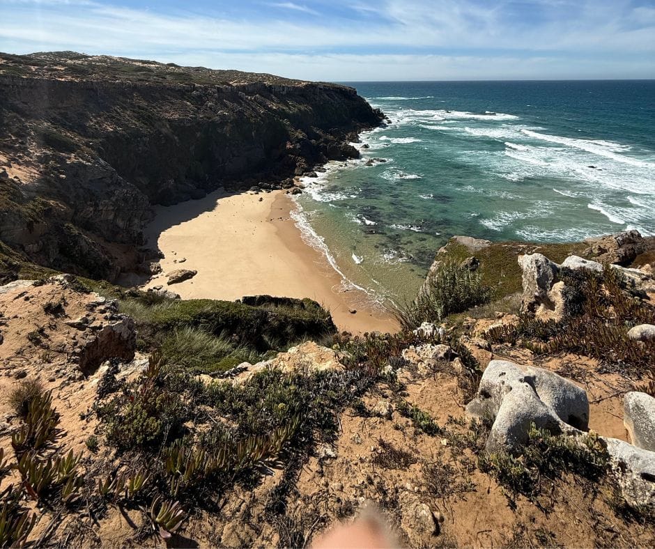 Sandy beach surrounded by rocky cliffs on the Fisherman's Trail in Portugal.