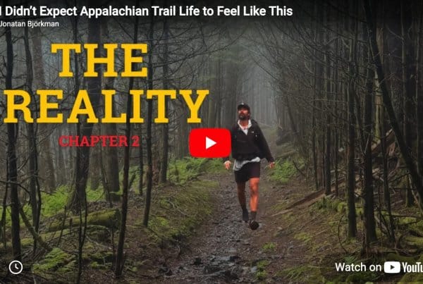 A person wearing a cap and hiking gear walks on a rocky forest trail, surrounded by leafless trees and green moss, with text reading "The Reality Chapter 2.