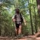 A hiker moving fast down a muddy Appalachian Trail section with exposed roots and brown earth