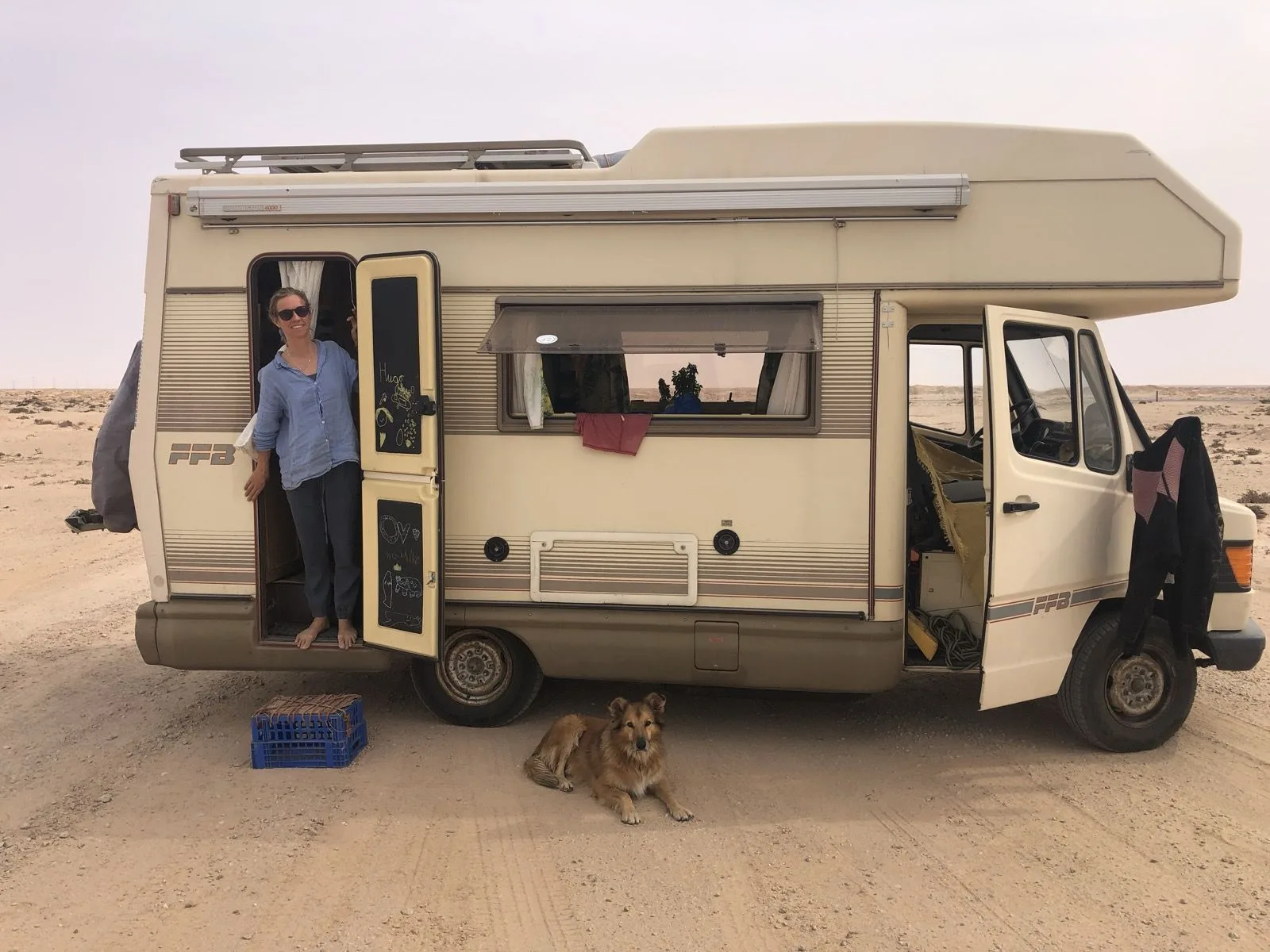 Suzanne in the door of her campervan with her dog Wingo in Western Sahara