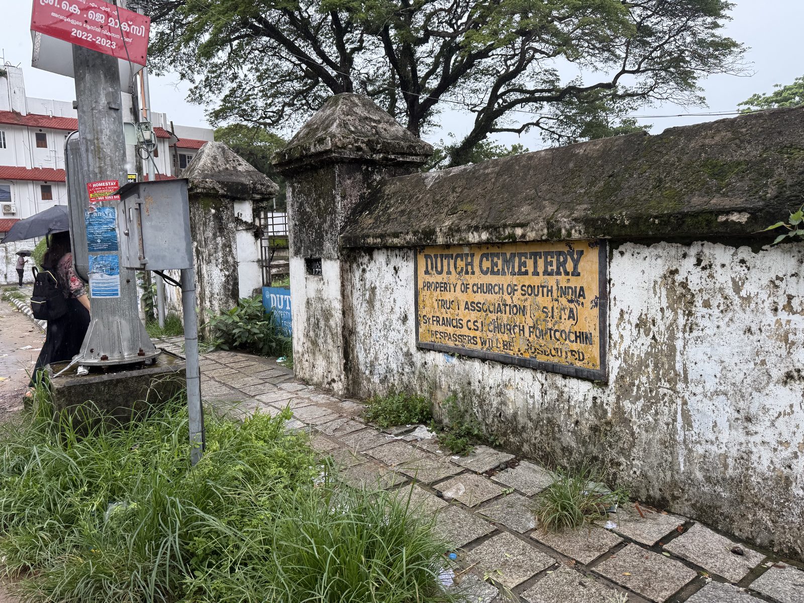 The weathered white wall and sign of the Dutch cemetery in Fort Kochi, Kerala