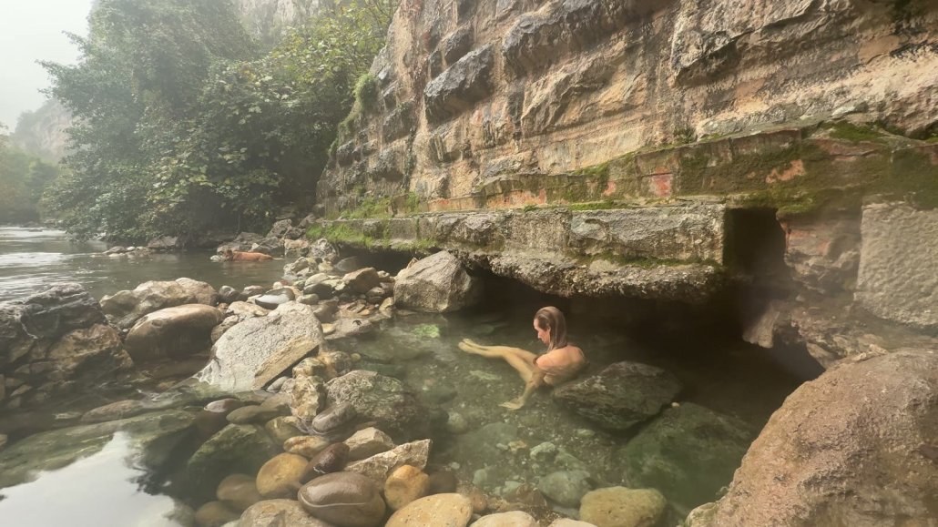 Suzanne in a natural hot spring pool under the rocks by the river