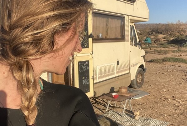 Suzanne in her wetsuit next to her old Mercedes camper van, with Wingo the dog